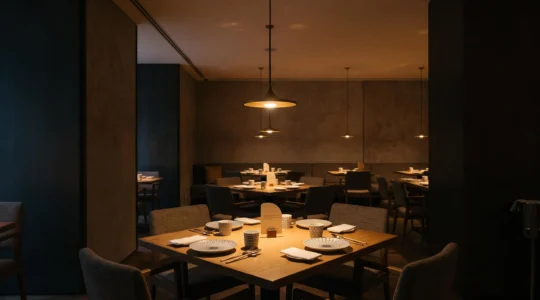 Salle de restaurant élégante baignée d'une lumière chaude et tamisée, illustrant comment réduire la facture d'éclairage sans perdre en ambiance